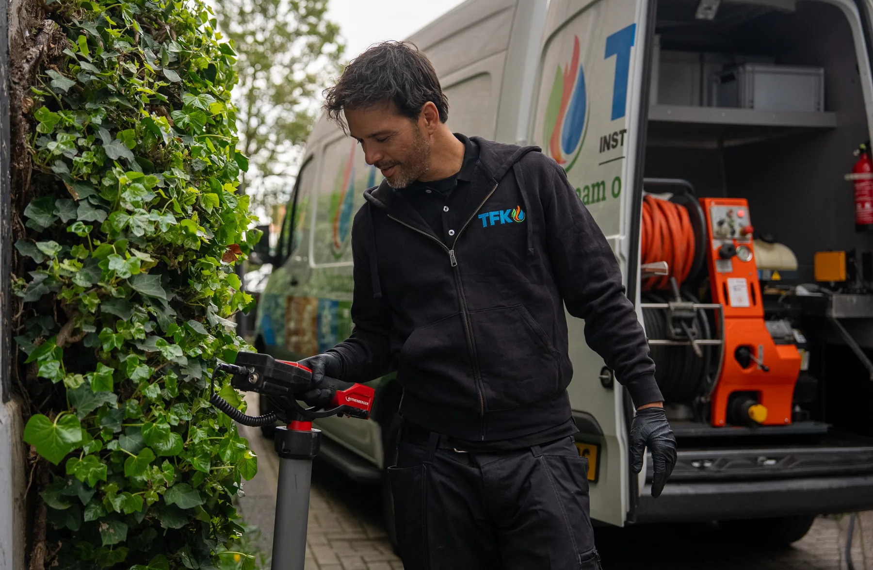 Monteur met professionele ontstoppingsmachine bij servicewagen